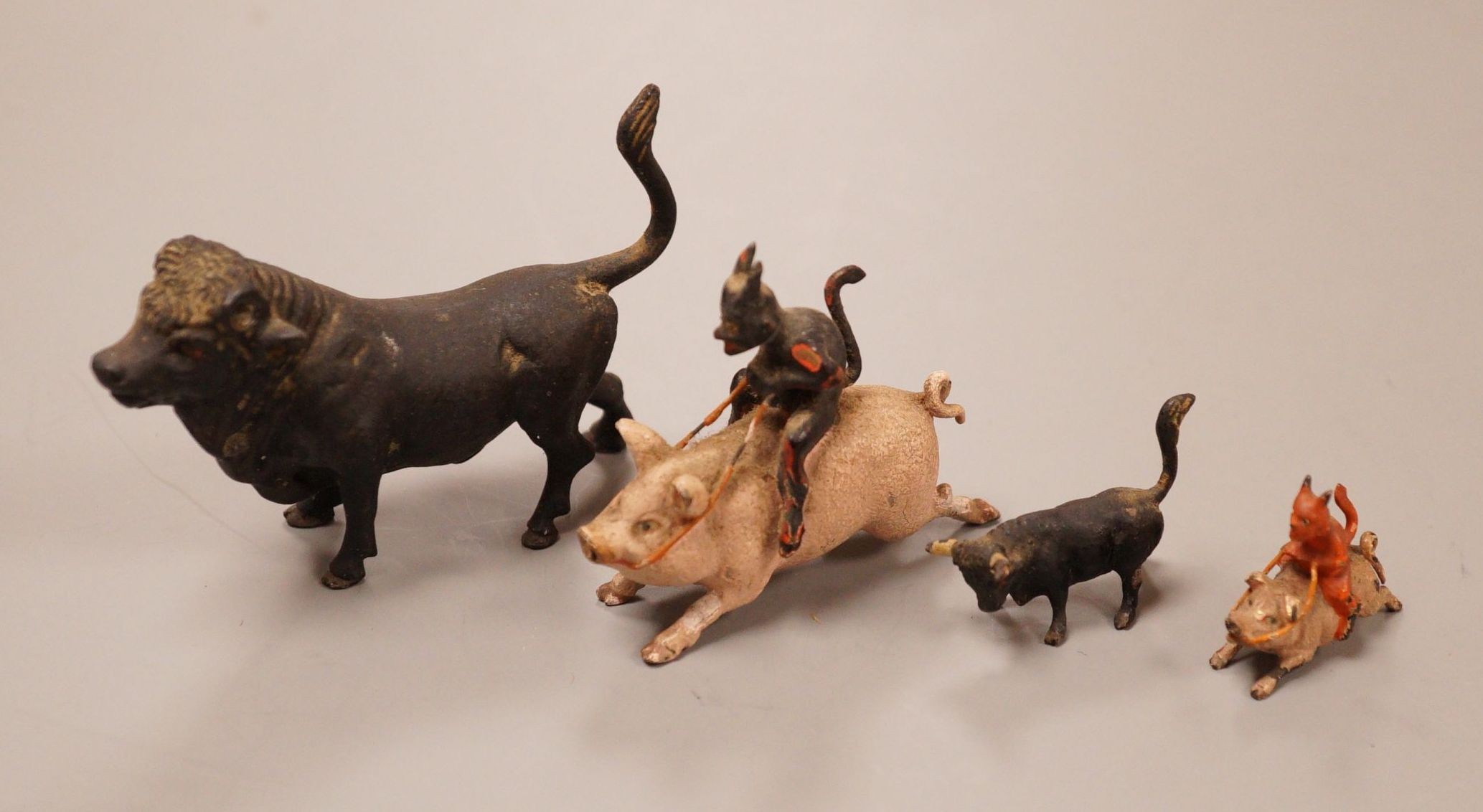 Four Austrian cold painted bronze miniature groups or figures, two of the devil riding a pig and two of cattle, tallest 4cm